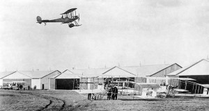 Montrose Air Station, Broomfield, UK, in 1914. Overhead a BE.2 flies while two MF.7 aircraft are prepared on the ground.  Credit:  UK Government